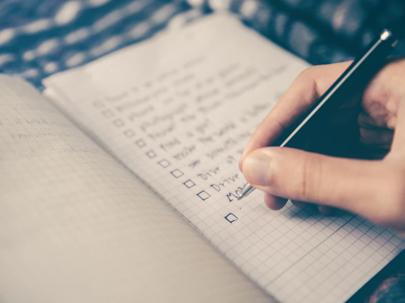 A hand checking items on a written planning list